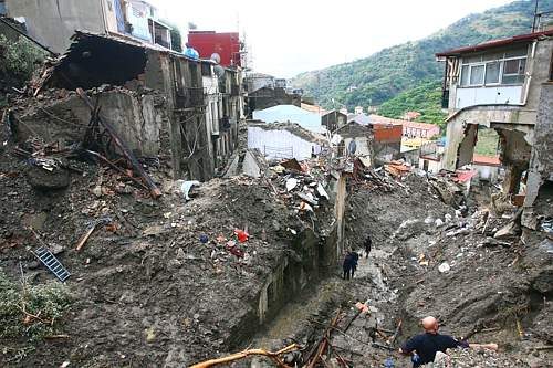 People walk through debris and mud in Giampilieri near Messina, southern Italy, Saturday, Oct. 3, 2009, the day after rivers of mud unleashed by heavy rains flooded parts of the Sicilian city of Messina, causing victims and several people missing. (AP Photo/Carmelo Imbesi)