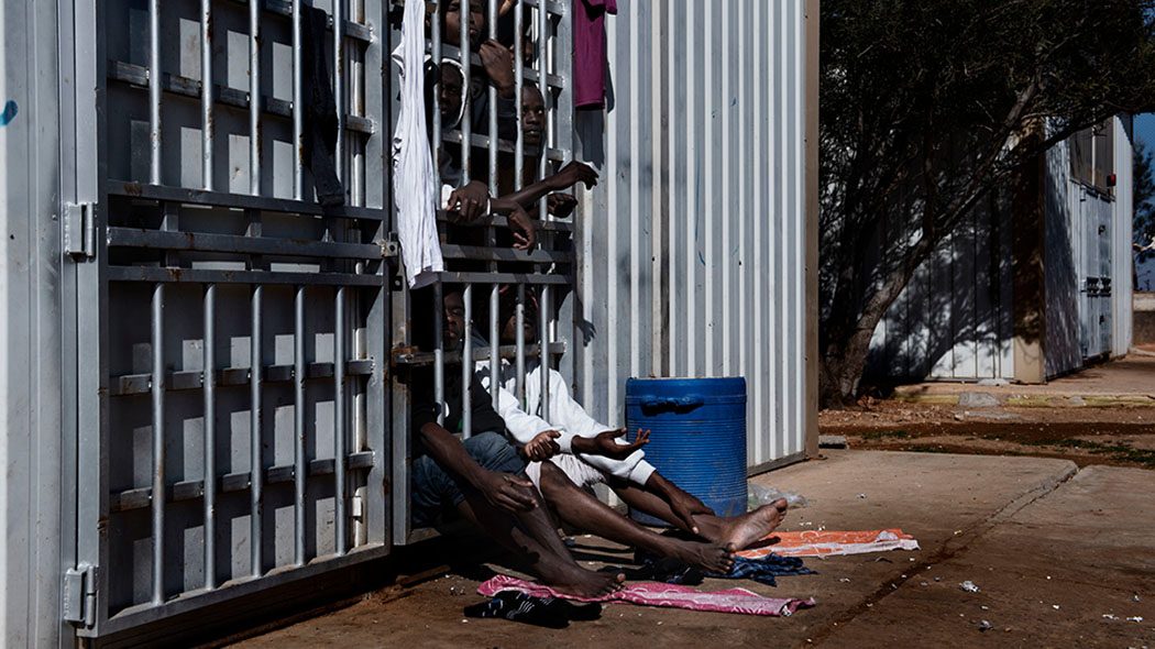 Migrants look out from behind the bars of a cell at the detention centre in Garian, Libya, Tuesday 31 January 2017. The Garian detention centre, located 70 kilometres south of Tripoli, was constructed in 2006 following an agreement between the Italian and Libyan governments in an attempt to stem the flow of migrants reaching Italy. When UNICEF visited the centre on 31 January 2017, the population consisted of 27 women (four of whom were pregnant), one 11-month old child, a four year old, as well as 1,352 men - of which 250 were under the age of 16. The centre is at the crossroads of areas controlled by different militias fighting with each other: the Warshafana, the militias of Tripoli and the militias who support Haftar in Benghazi. For this reason it is a very dangerous centre, for officers who work there and for migrants in detention. The detention centre is currently managed by the Libyan National Army, and most migrants remain there for a period of 8 to 10 months according to the manager Abdalhamad Altunisa. "Children are often alone, they cross 2000 kilometres of desert without their families, and they are rescued at sea without documentsî, said Altunisia ìthis makes it difficult for us to know their real nationality and age. Before 2014 we brought them back to the border between Nigeria and Libya to take them back to their countries, but after the last civil war it was much more difficult. Those areas are dangerous even for usî. Migrants who were being held in the cells said they are rarely allowed out. Many of the those being held are sick, and some detainees are said to have passed away because they have no access to medical care. The director of the centre, Altunisa, said "the official government [of Sarraj] does not give us the money to pay salaries and to pay those who bring us food. So often we do not have enough food or drinking water. This winter was particularly cold and in recent weeks 15 migrants froze to death."

Libya is a country in turm